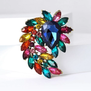Detailed macro view of vintage gold brooch with colorful crystals and blue pear-shaped stone