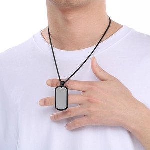 Close-up of a two-tone black and silver stainless steel dog tag necklace worn on a model