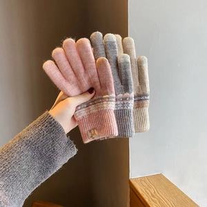 Detail of three pairs of thick knitted gloves in pink grey and beige with jacquard pattern