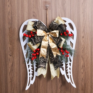 Christmas wreath with white angel wings, leopard print bow and red berries on wood wall