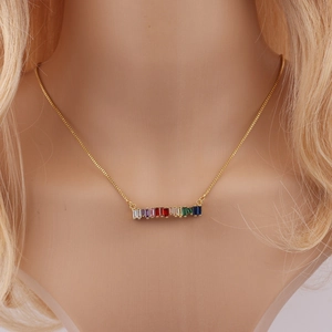 Close-up of golden necklace with a rainbow row of rectangular colored gemstones on neck