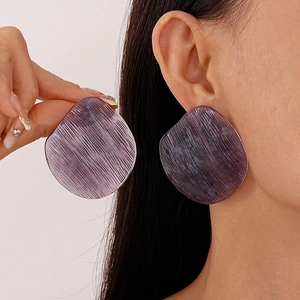 Detailed macro view of purple resin irregular round stud earrings with vertical textures
