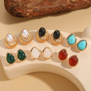 Elegant gold drop earrings with turquoise and pearls on an aesthetic natural stand