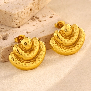 Macro detail of golden layered fan-shaped earrings with textured dotted surface