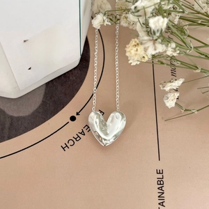 Macro detail of irregular matte heart pendant necklace in silver for women