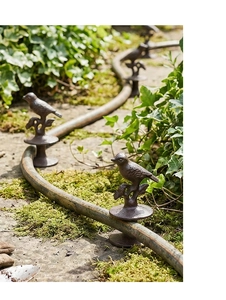 Close-up of vintage cast iron bird hose guide stake in an English garden setting