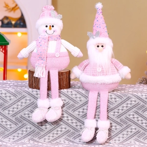 Dettaglio di bambole natalizie rosa con paillettes e gambe lunghe su legno
