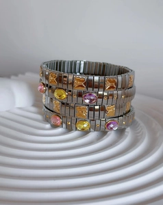 Detail of stretch bracelet featuring pink gems and gold butterfly charms on silver links