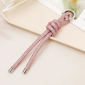 Pink rhinestone knotted car keychain with silver ring on a beige tray display