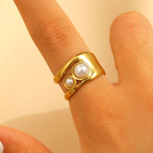 Detail of gold wide irregular band ring featuring double white pearls in a modern design