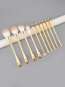 Detail of 10-piece gold makeup brush set with gradient bristles on a grey background
