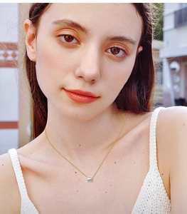 Close-up of a gold necklace with a rectangular emerald cut pendant on a model's neck