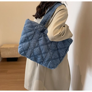 Détail du grand sac cabas en denim bleu avec surpiqûres en losanges sur un sac de mannequin