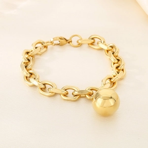 Detail view of a chunky gold stainless steel chain bracelet with a large spherical charm