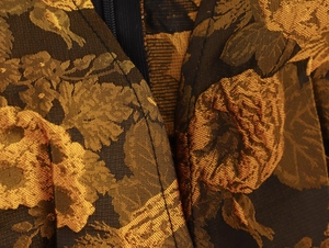 Detail van gouden bloemen jacquard stof en zwarte onzichtbare rits op de mouw van de jurk
