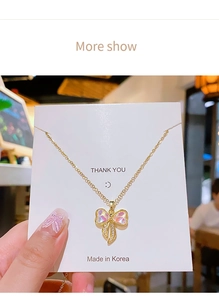 Dettaglio di una collana a fiocco dorato con interno rosa cangiante e accenti di zirconi