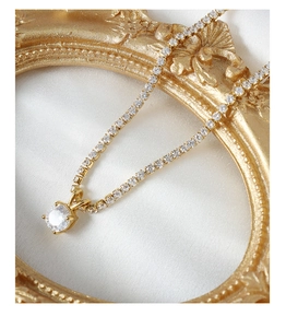 Close-up of 18K gold plated necklace featuring full zircon chain and large round solitaire