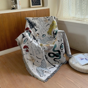 Bohemian knit camping blanket with wolf and forest patterns and fringe trim on a chair