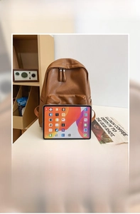 Large brown leather backpack shown with iPad and newspaper to highlight spacious capacity