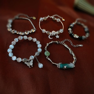 Detailed set of butterfly and cat eye stone bracelets with star pendants on dark background