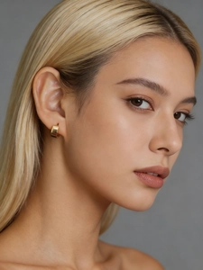 Close-up of elegant wide chunky gold hoop earring worn by a model on a grey background
