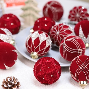 Set of red flocked Christmas balls with gold glitter patterns on a display tray