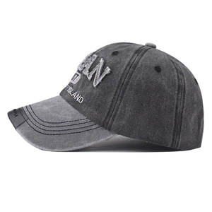 Detailed side view of washed dark grey denim baseball cap with AN 87 ISLAND embroidery