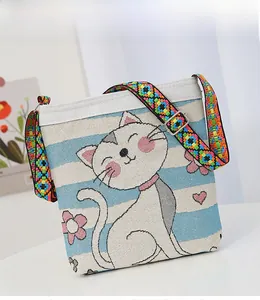 Close-up of canvas bag with cat embroidery and colorful woven bohemian strap