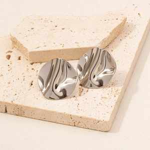 Macro view of silver 304 stainless steel wavy round earrings on minimalist stone base