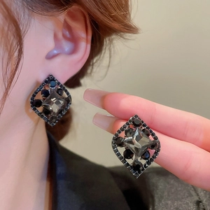 Macro shot of geometric black rhinestone drop earrings with dark plating detail