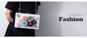 Detail of floral acrylic clutch featuring 3D fabric flowers and golden metal chain strap