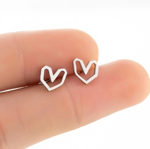 Minimalist hollow heart stud earrings in polished stainless steel held for size scale