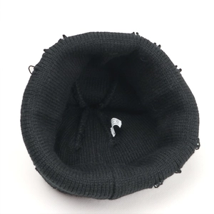Detail view of black knit beanie with distressed holes and ribbed texture interior