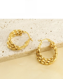 Detail of twisted 18K gold plated earrings showing intricate rope texture on limestone