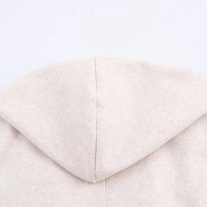 Detailed close-up of soft beige fleece material and hood seam stitching on the coat
