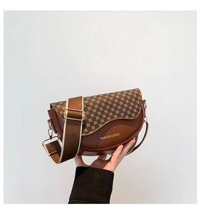 Detail of a brown leather saddle bag featuring geometric prints and a wide strap