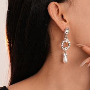 Detail of elegant drop earring with crystal flower and white pearl on model