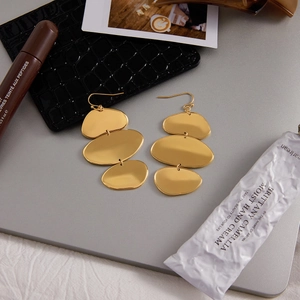 Détail de boucles d'oreilles ovales dorées géométriques sur un bureau de style
