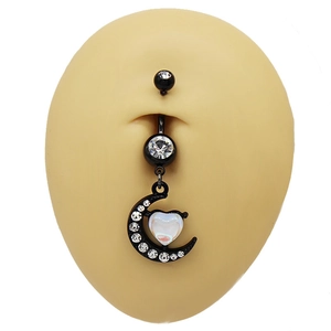 Macro detail of black crescent moon belly ring with sparkling heart gemstone on skin