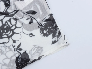 Close-up of white chiffon fabric with black floral prints and garment care label details