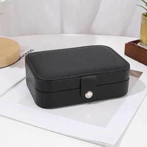 Detail of a black leather jewelry box with a silver snap button on a desk