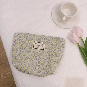 Detailed view of mint floral makeup bag with elegant fabric texture on white quilted surface