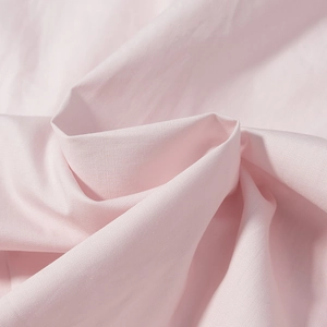 Gros plan sur la texture du tissu en coton rose avec drapé doux et plis naturels