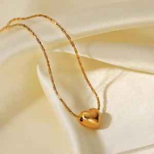 Elegant 18K gold-plated heart pendant necklace on soft white silk fabric background