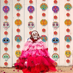 Colorful Day of the Dead banner with sugar skulls and flowers on a white fence