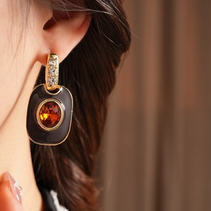 Close-up of vintage enamel gold earring with amber gemstone and diamond accents