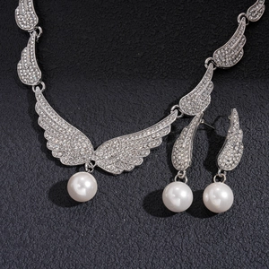 Silver angel wing jewelry set with rhinestones and round white pearls on a black background