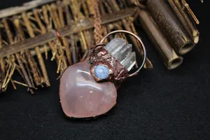 Detailed close-up of heart-shaped rose quartz pendant with copper accents and blue stone