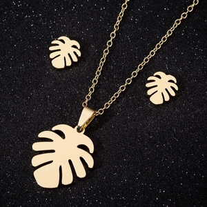 Elegant gold leaf pendant necklace and earrings set on a black sparkling background