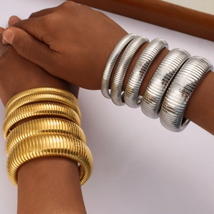Layered 18K gold and silver stainless steel flexible spring bangles worn on wrist